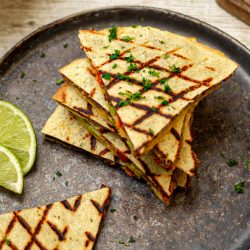 Mexikanische Quesadillas - Mit fruchtiger Tomaten-Avocado-Salsa Goldbraun geröstete Quesadilla-Hälften mit geschmolzener Käsefüllung, auf einem Teller angerichtet, daneben eine Schale mit Dip.