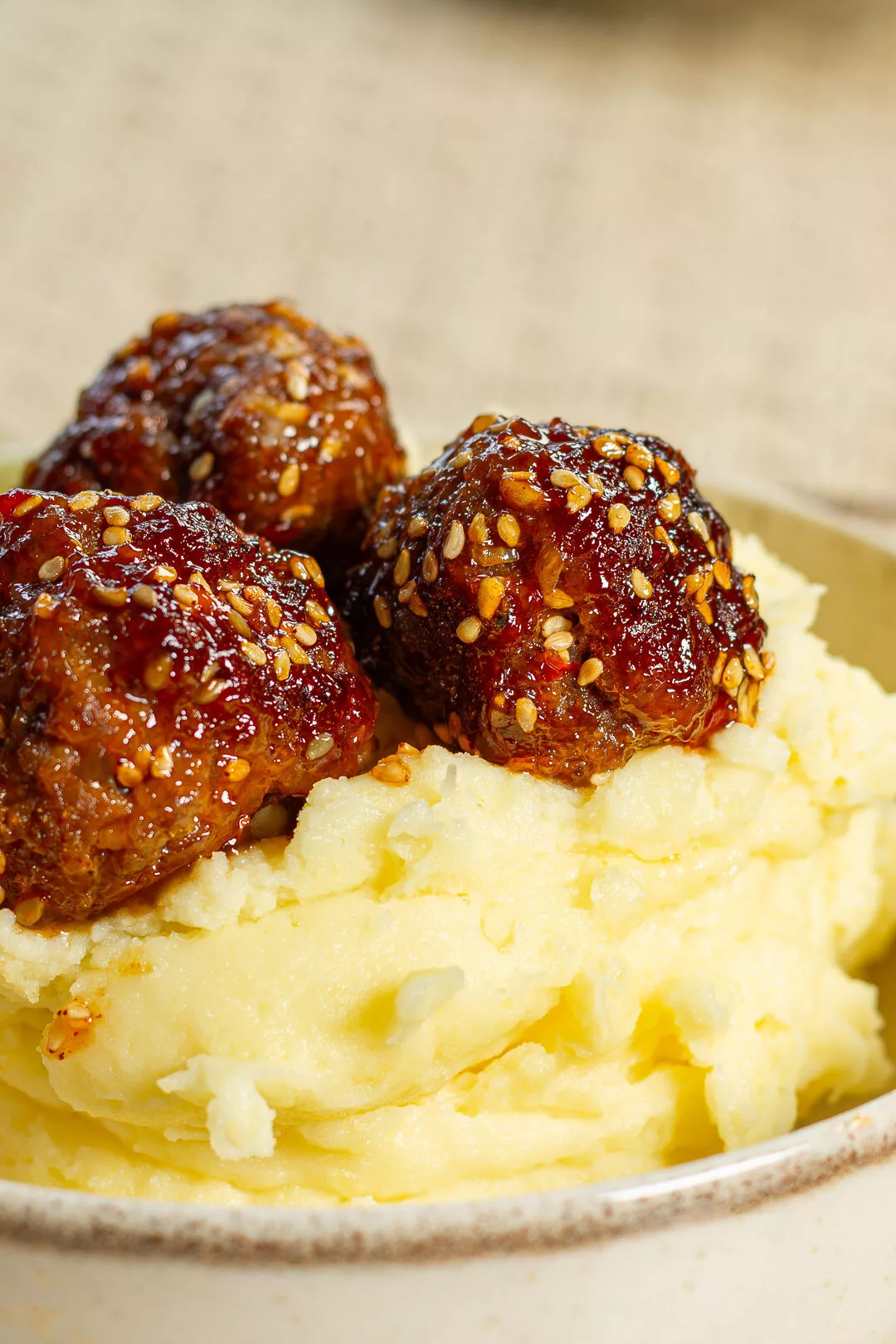 Saftig glasierte vietnamesische Meat Balls mit Kartoffelstampf in einer Schale, garniert mit Sesam.