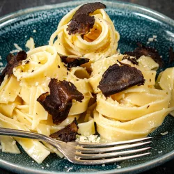 Pasta al Tartufo – Klassische Trüffelpasta mit Parmesan Cremige Trüffelpasta mit Tagliatelle, Parmesan und schwarzen Trüffelscheiben auf einem Teller angerichtet.