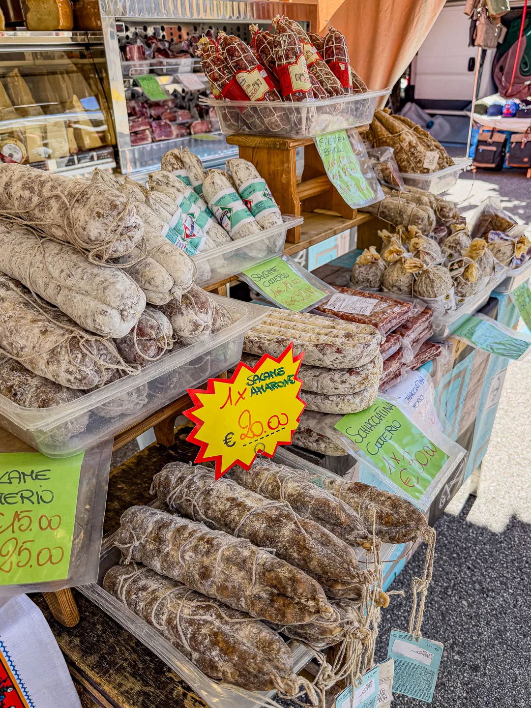 Marktstand in Cannero Riviera am Lago Maggiore mit verschiedenen luftgetrockneten Salamis, Würsten und regionalen italienischen Spezialitäten in Körben und Auslagen.