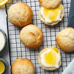 Frisch gebackene goldbraune Scones mit cremiger Zitronenfüllung, dekoriert und serviert auf einem Teller – perfekt für Frühstück oder Brunch