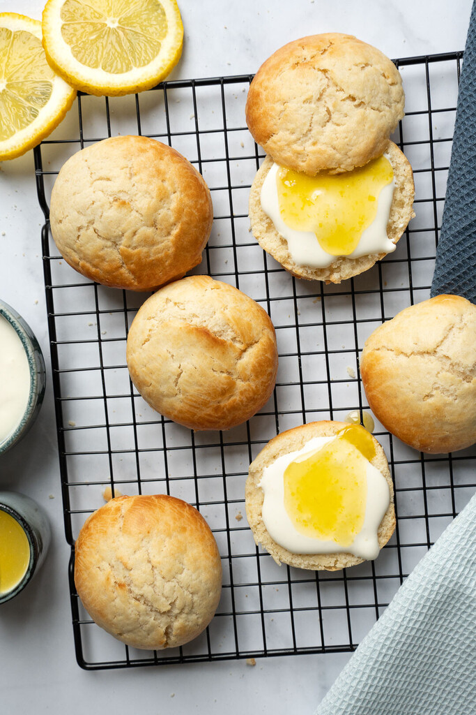 Frisch gebackene goldbraune Scones mit cremiger Zitronenfüllung, dekoriert und serviert auf einem Teller – perfekt für Frühstück oder Brunch
