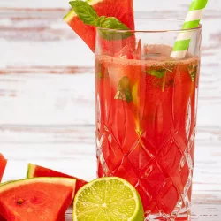 Erfrischendes Wassermelonen Limonade Rezept mit Eiswürfeln, Wassermelonenstücken und frischem Basilikum in einem Glas.