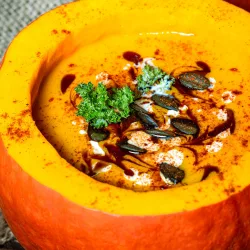 Hokkaido Kürbissuppe nach Mamas Rezept – cremig und einfach Cremige Kürbissuppe in einem ausgehöhlten orangefarbenen Kürbis, garniert mit Kürbiskernen, Petersilie, Sahne und dunklem Öl.