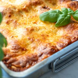 Frisch gebackene Lasagne mit goldbrauner Käsekruste in einer Auflaufform, garniert mit Basilikum und leicht knuspriger Oberfläche
