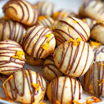 Hausgemachte Orangen-Schoko-Kekse mit Zartbitterschokoladen-Glasur und frischem Orangenabrieb auf einem hellen Teller.