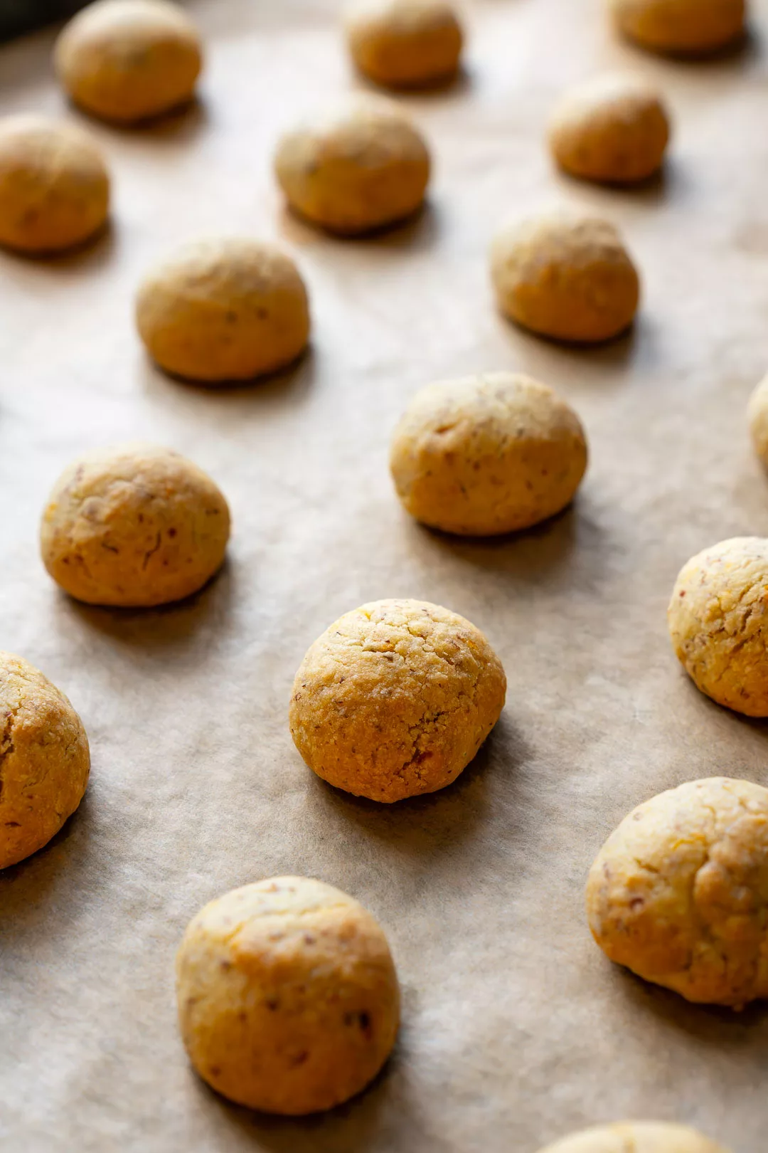 Goldbraun gebackene Orangen-Wölkchen Kekse auf Backpapier direkt nach dem Backen, Nahaufnahme von runden, weichen Plätzchen auf einem Backblech.