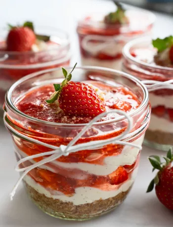 Erdbeer-Tiramisu im Glas mit Keksboden, cremiger Mascarpone-Quark-Schicht, fruchtigem Erdbeer-Topping und frischer Erdbeere als Dekoration.