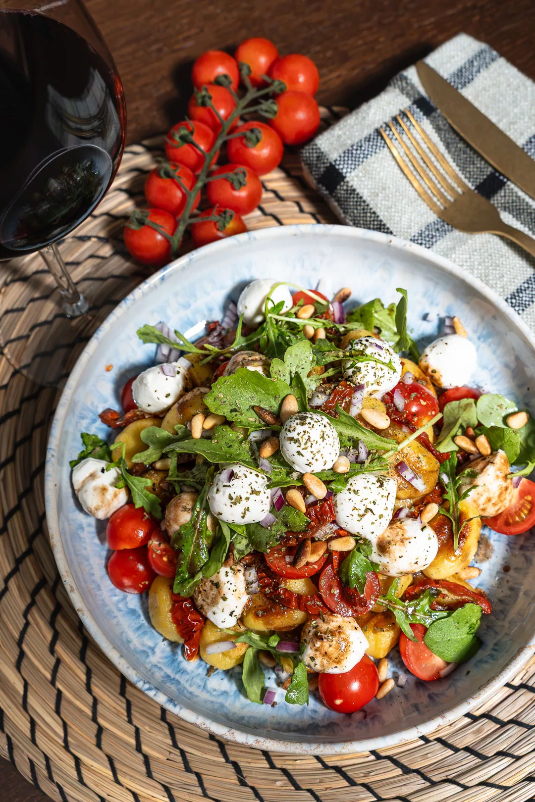 Mediterraner Gnocchi-Salat mit Mini-Mozzarella, getrockneten Tomaten und Rucola in einer Schüssel angerichtet.