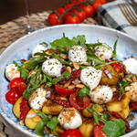 Mediterraner Gnocchi-Salat mit Mini-Mozzarella, getrockneten Tomaten und frischem Rucola in einer Schüssel serviert.