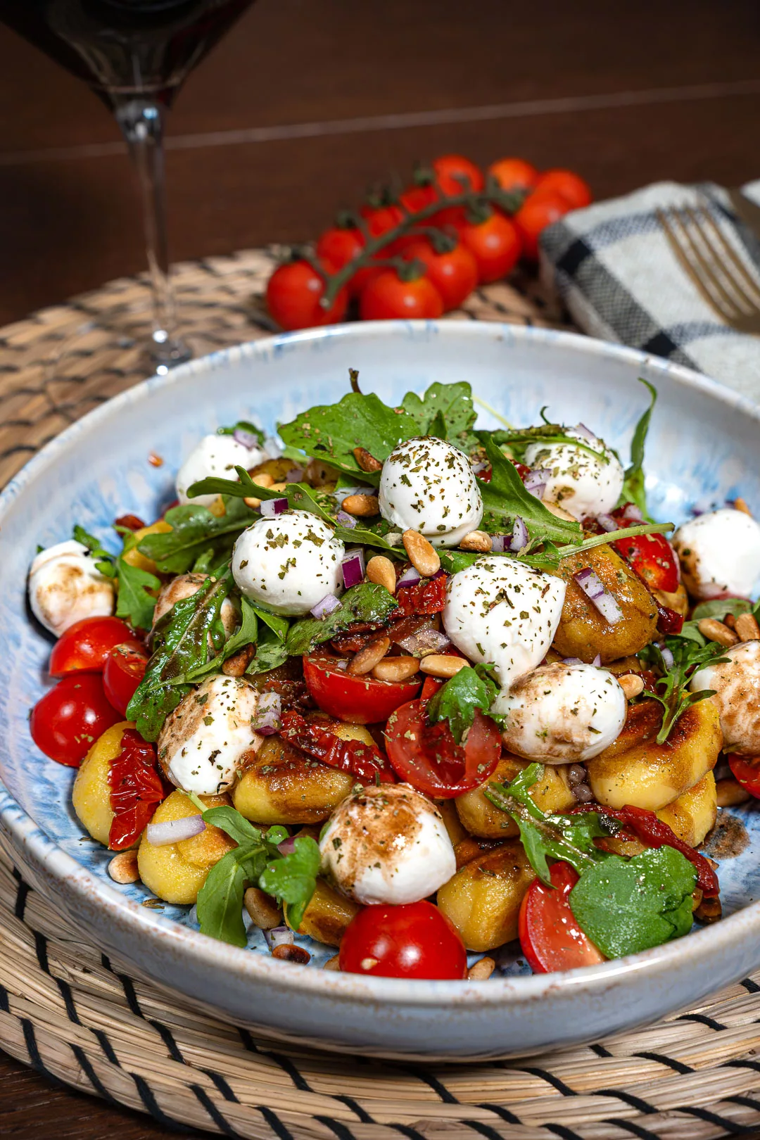 Mediterraner Gnocchi-Salat mit Mini-Mozzarella, getrockneten Tomaten und frischem Rucola in einer Schüssel serviert.