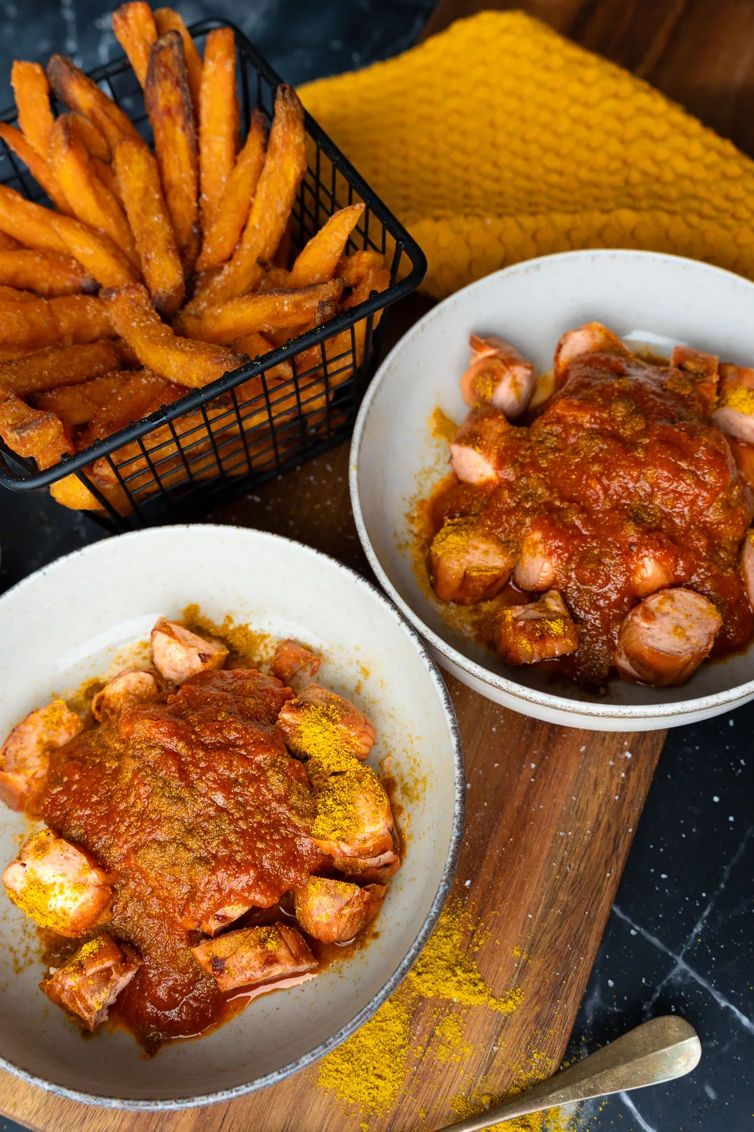 Selbstgemachte Currywurst mit würziger roter Currysoße, Currypulver und Pommes als einfaches deutsches Imbissgericht.