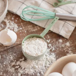 Mengen umrechnen beim Backen: Backzutaten wie Mehl in Schalen, Eier und Zucker auf einer Arbeitsfläche in der Küche.