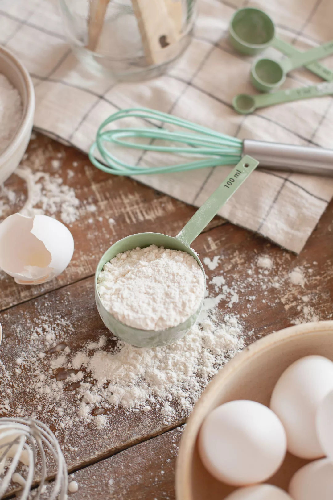 Mengen umrechnen beim Backen: Backzutaten wie Mehl in Schalen, Eier und Zucker auf einer Arbeitsfläche in der Küche.