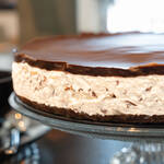 Draufsicht auf eine Bananensplit Torte mit Schlagsahne, Bananenscheiben und Schokoladensauce auf einer Kuchenplatte.