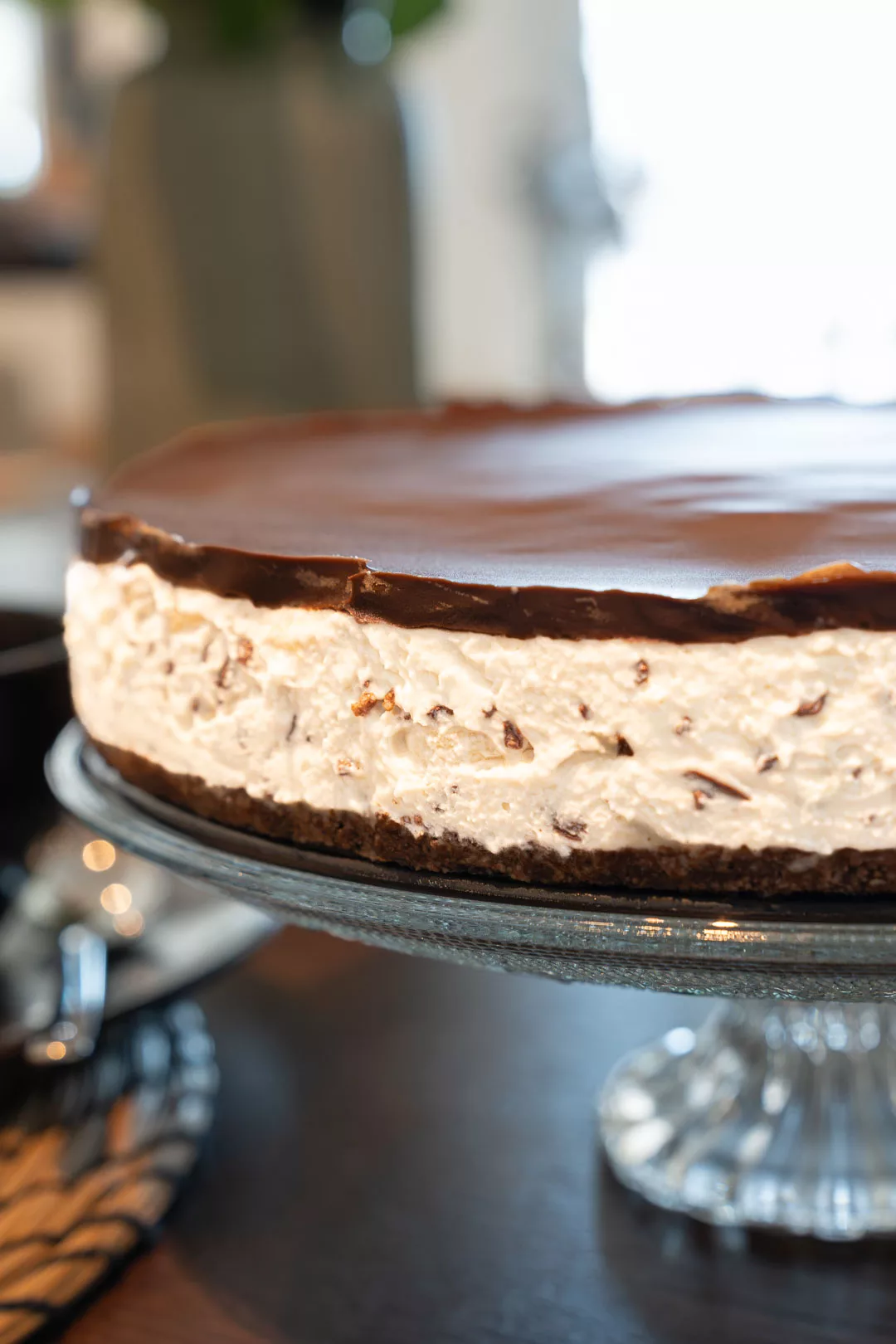 Draufsicht auf eine Bananensplit Torte mit Schlagsahne, Bananenscheiben und Schokoladensauce auf einer Kuchenplatte.