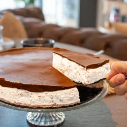 Bananensplit Torte ohne Backen: Cremiger Eisdielen-Klassiker als No Bake Cake Stück Bananensplit Torte ohne Backen auf Teller mit Frische Bananenscheiben, Schlagsahne und Schokoladensauce garniert.