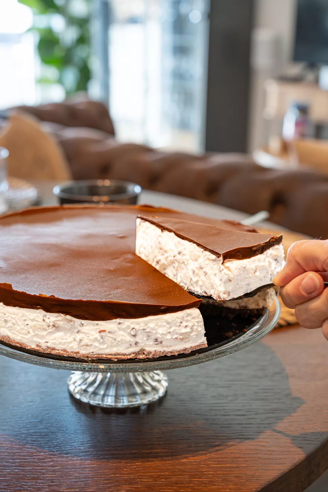 Stück Bananensplit Torte ohne Backen auf Teller mit Frische Bananenscheiben, Schlagsahne und Schokoladensauce garniert.