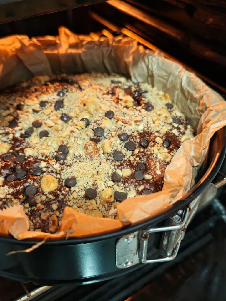 Goldbrauner Kuchen in runder Springform auf dem Backofenrost im Ofen.