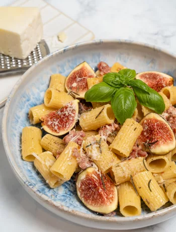 Pasta mit frischen Feigen und gebratener Salsiccia serviert auf einem Teller.