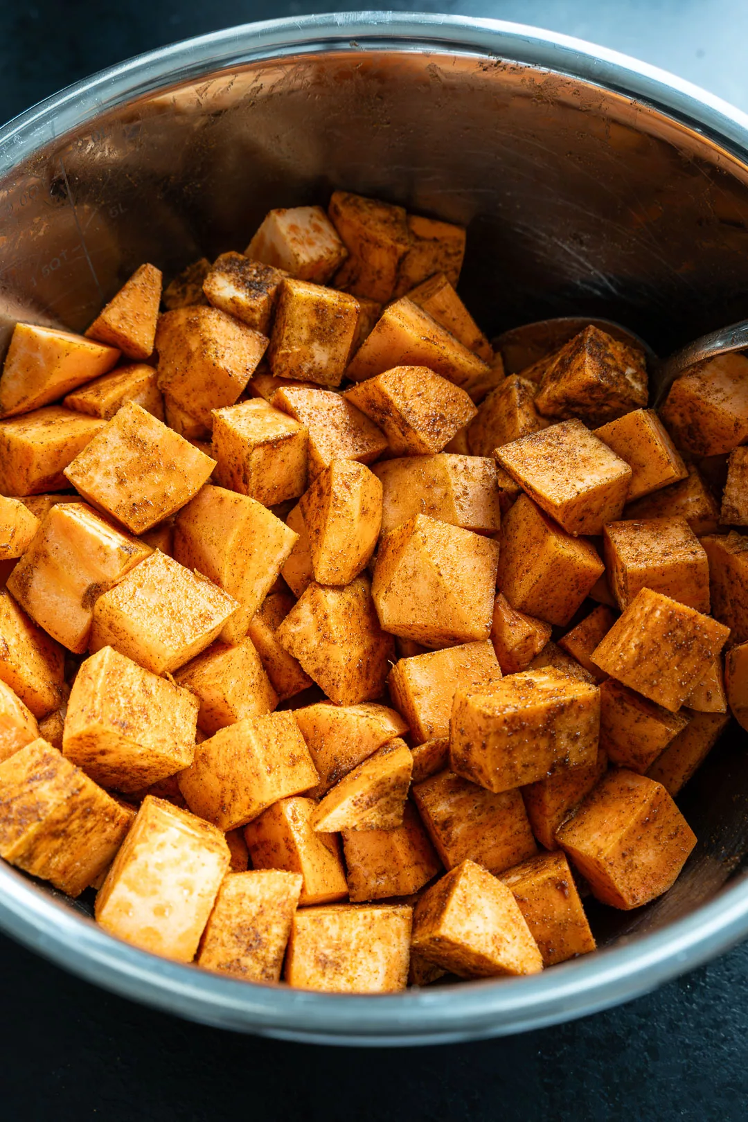 Gewürfelte, gewürzte Süßkartoffeln auf Vorbereitungsfläche vor dem Backen.