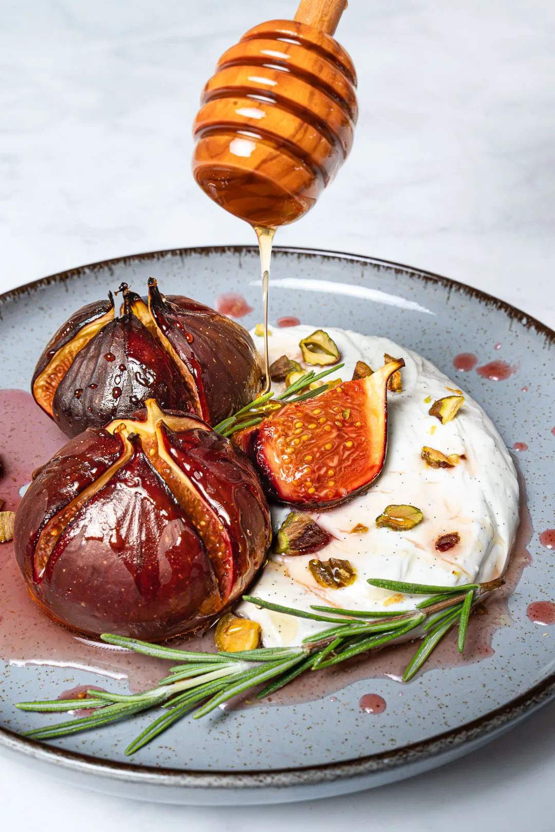 Gebackene Feigen mit Mascarpone auf einem rustikalen Teller, beträufelt mit Honig und gehackten Nüssen.