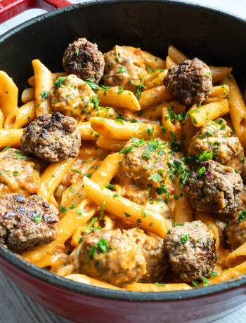 One Pot Pasta mit Meatballs in Tomatensauce in einer großen Pfanne, garniert mit Mozzarella und frischer Petersilie.