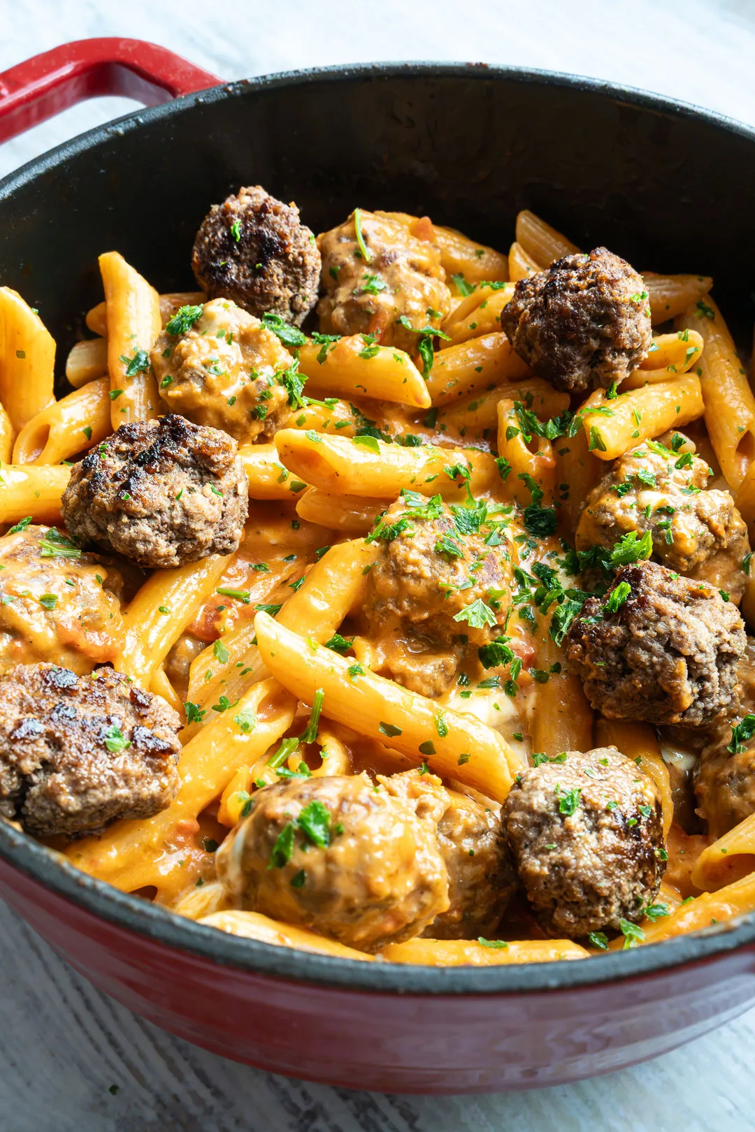 One Pot Pasta mit Meatballs in Tomatensauce in einer großen Pfanne, garniert mit Mozzarella und frischer Petersilie.