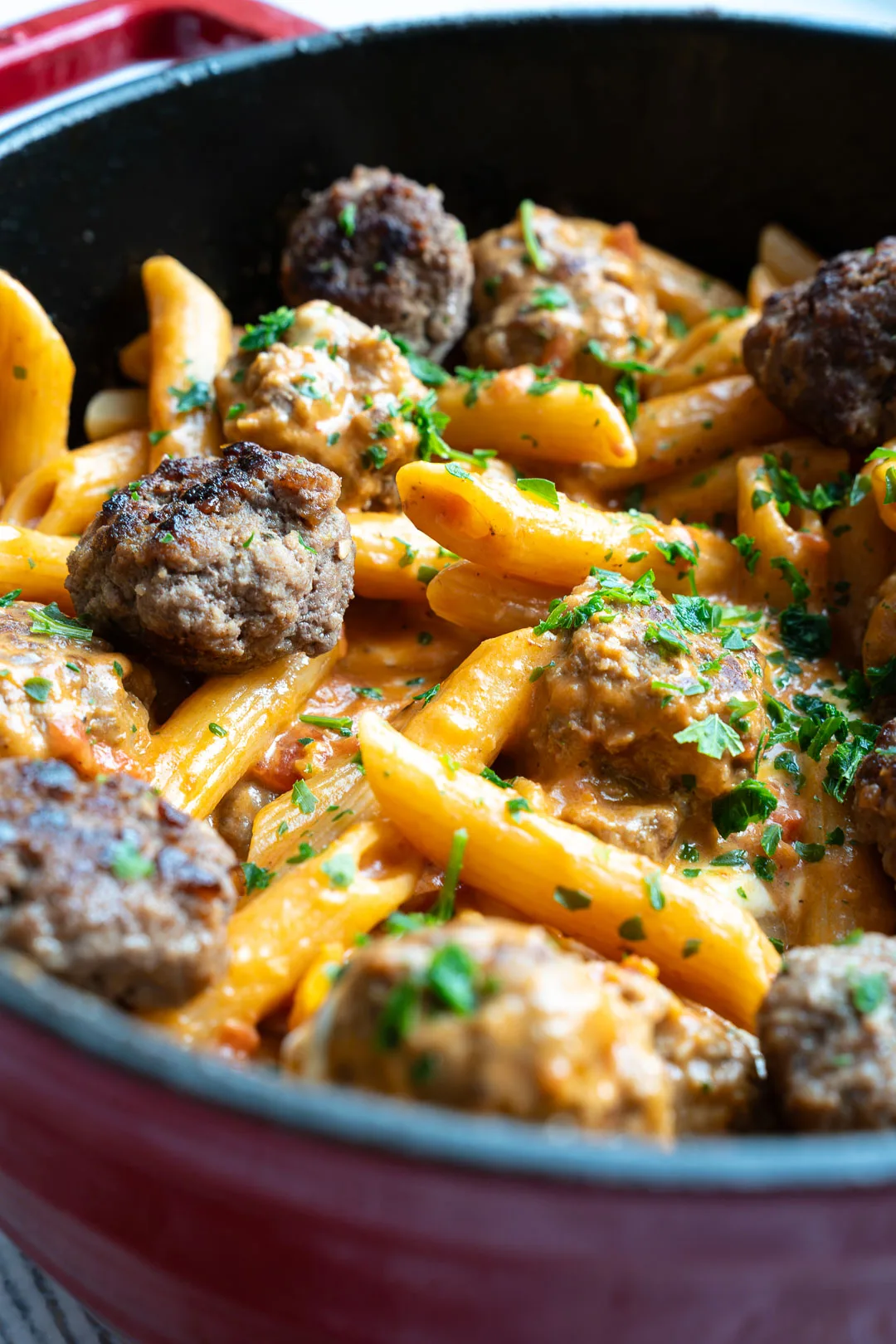 Schnelle One Pot Pasta mit Meatballs und Mozzarella in roter Sauce, serviert in dunkler Schale mit frischer Petersilie.