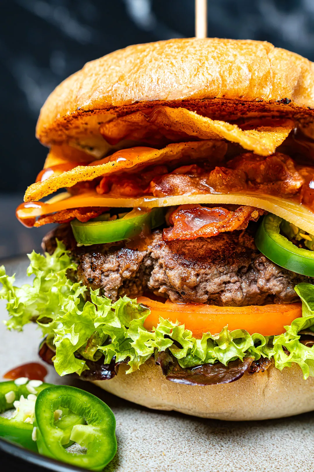 Tex Mex Burger auf einem Teller, mit Rindfleisch-Patty, Cheddar, dunklem Bohnen-Mash, Jalapeños und roten Zwiebeln.